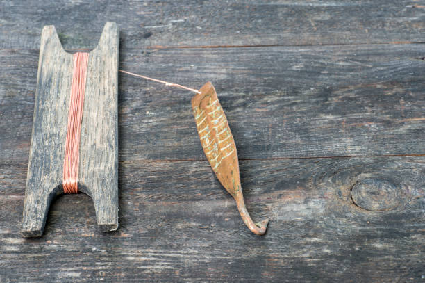 istock Ancient tackle for vertical flashing predatory fish. Copper forged spinner and reel with rope on wooden rustic background 1163322106