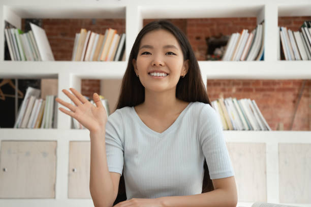 uśmiechnięta azjatycka dziewczyna pozdrawiając machając mając rozmowę wideo - internet dating audio zdjęcia i obrazy z banku zdjęć
