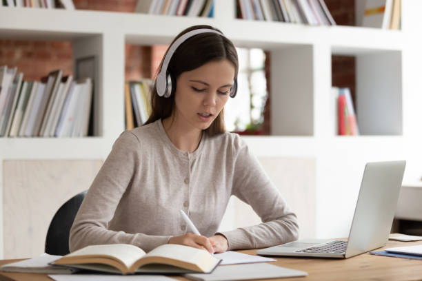 skoncentrowana dziewczyna w słuchawkach bluetooth studiujących w domu - child writing education nerd zdjęcia i obrazy z banku zdjęć