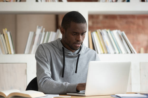 istock Serious black male student studying with laptop at home 1163323481