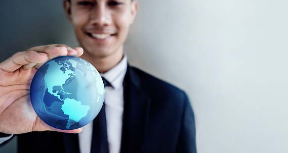 Globalization and Worldwide Concept. Happy Smiling Professional Businessman holding a Transparent Blue World Globe in Hand