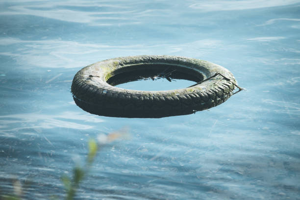 istock Environmental pollution: old tyre is lying in the water, coastline 1163328029