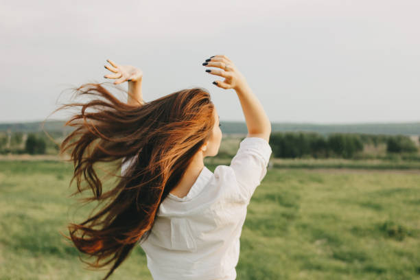 primo tempo ritratto di bella ragazza spensierata capelli lunghi in abiti bianchi in campo, vista da dietro. sensibilità al concetto di natura - capelli o peli foto e immagini stock