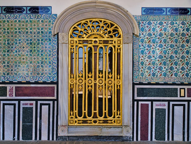 Window with golden railings and classical oriental design on tiled wall at Topkapi Palace in Istanbul, Turkey.
