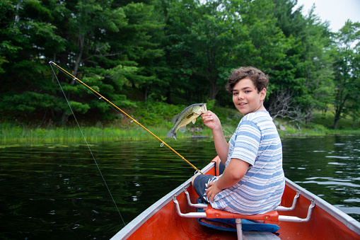 A teen fisherman holding a Largemouth bass.