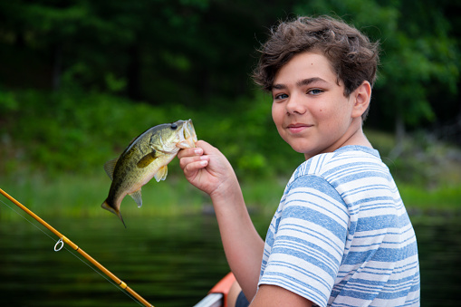 A teen fisherman holding a Largemouth bass.