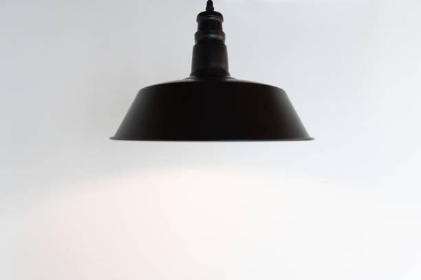 istock closeup of single black hanging lamp on white wall background. 1163342313