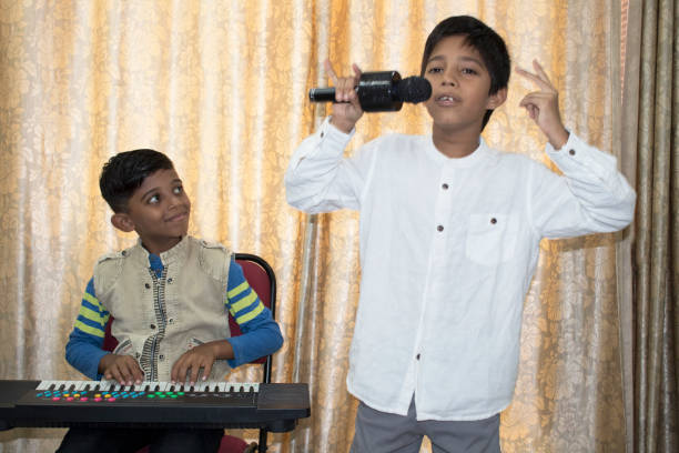 dos chicos tocando el piano y cantando una canción en el micrófono - curtain stage theater stage red fotografías e imágenes de stock