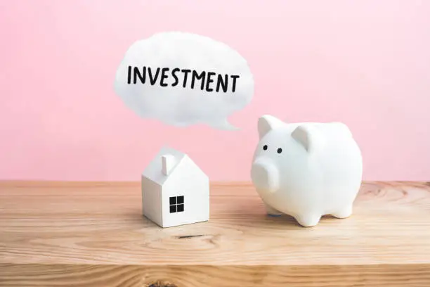 Photo of Home (house) mockup and piggy bank with investment text on wooden table