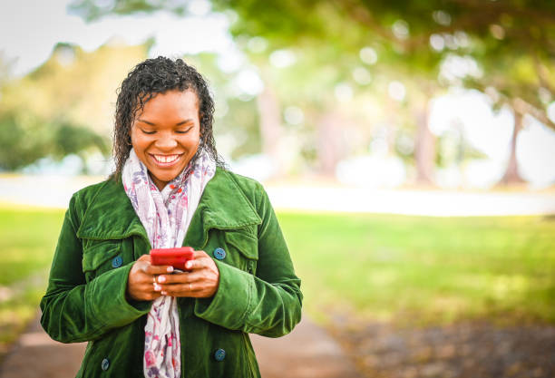 istock African American woman uses cell phone outdoors in a light jacket 1163355375