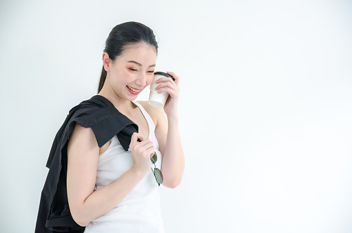 Pretty young asian business woman holding a cup of coffee and black tshirts. Isolated Studio portrait on white background.