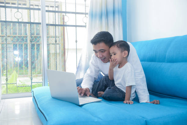 istock Malaysian father using laptop with his little boy at home 1163359821