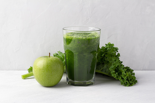 Green smoothie with kale cabbage and apple on a gray background. delicious healthy vegan food