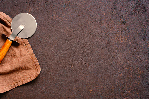 Brown textured background with linen napkin and pizza knife