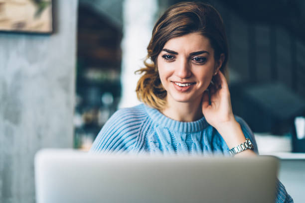 istock Pretty young woman student watching interesting video on modern laptop device using wireless internet connection.Hipster girl with smile on face reading good news on website on netbook 1163365878