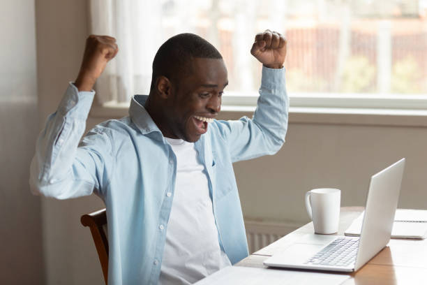 istock Happy african guy feels overjoyed celebrate online success 1163367333