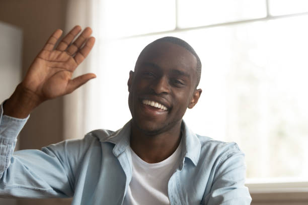 istock Head shot cheerful african guy look at camera wave hand 1163367353