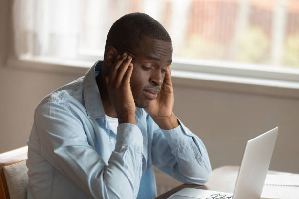 istock African guy sitting near computer rubbing temples feels unwell 1163367354