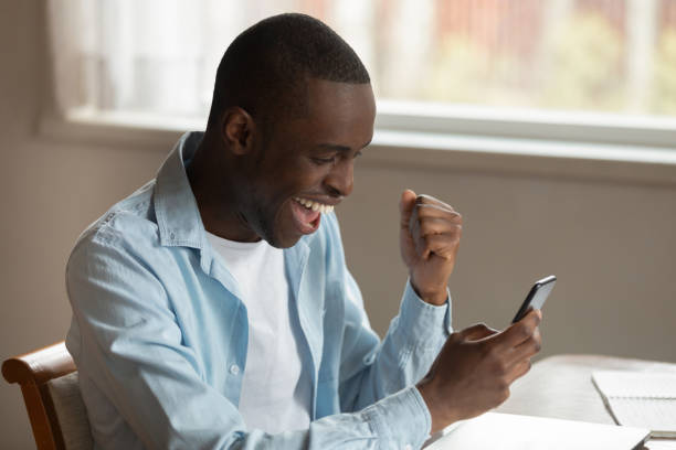 African man look at smartphone feels excited received good message
