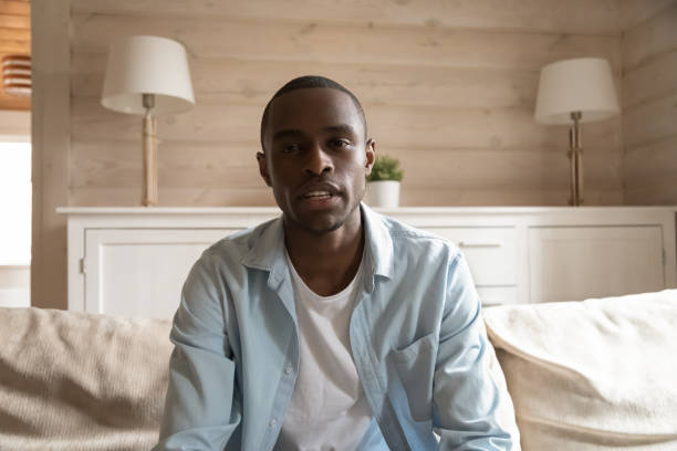 Young african guy recording vlog at home looking at webcam