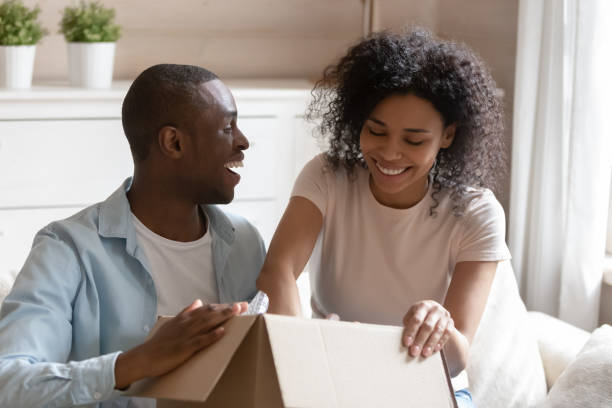 istock African couple unpack carton box sitting on sofa feels happy 1163367413
