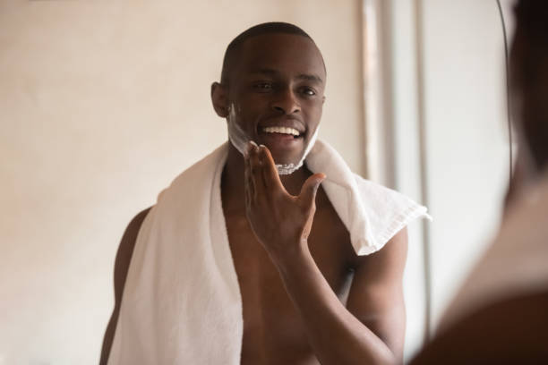 istock African young man looking in mirror applying shaving foam 1163367421