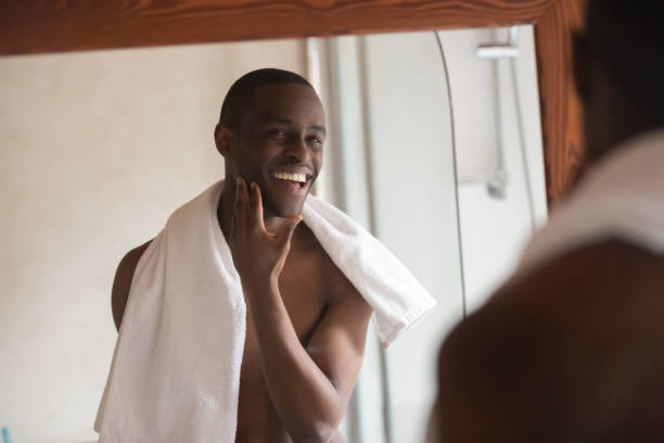 istock Shaved handsome african man looking in mirror feels satisfied 1163367428