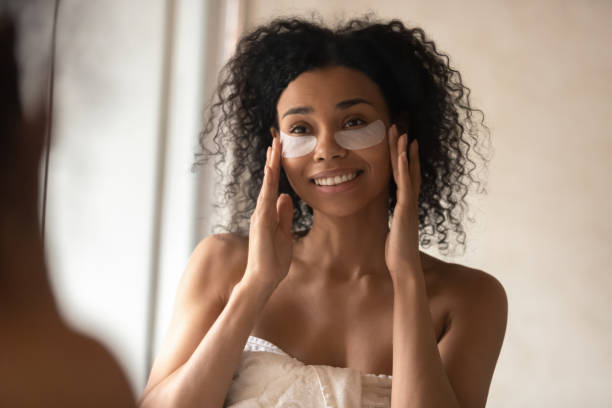 istock Attractive african woman applied under-eye patches looking in mirror 1163367457