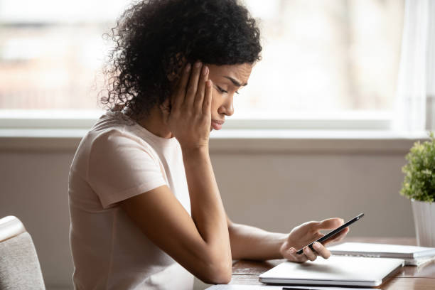 istock African woman looking at mobile phone screen feels upset 1163367463