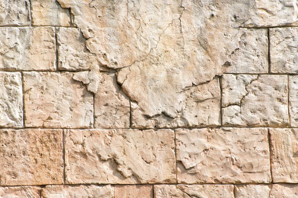 istock Old gray wall of rectangular stone blocks with remnants of plaster. Abstract background 1163367806