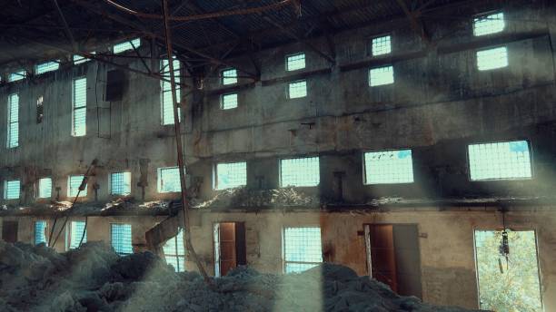 istock Abandoned destroyed factory from the inside with sunbeams that pass through the windows 1163370167