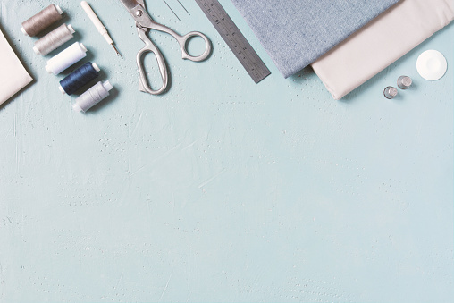 Blue textured background with sewing tools, copy space