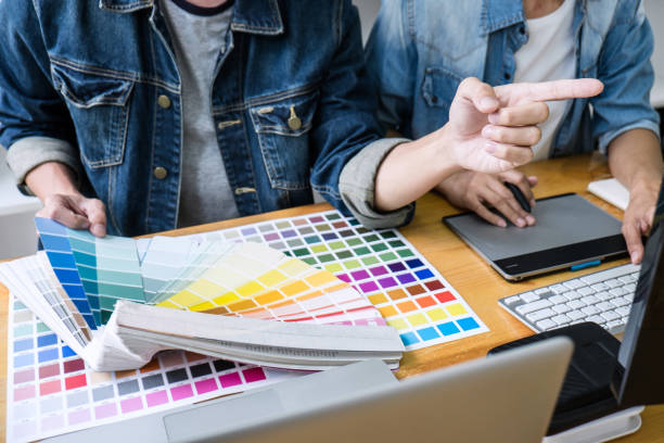 istock Two colleagues creative graphic designer working on color selection and drawing on graphics tablet at workplace, Color swatch samples chart for selection coloring 1163371933