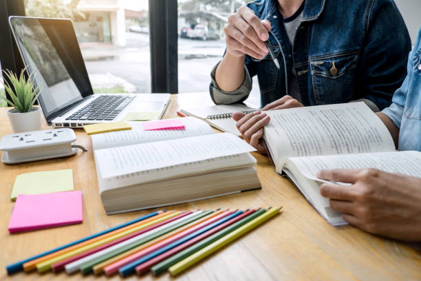 istock Education, teaching, learning, technology and people concept. Two high school students or classmates with helps friend do homeworks learning in classroom, Tutor books with friends 1163371938