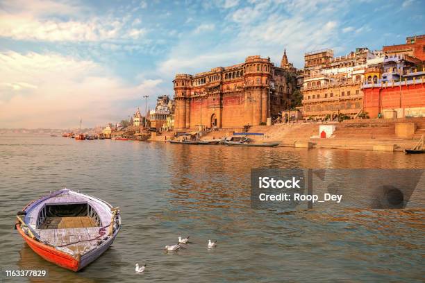 Varanasi Ancient City Architecture At Sunset With View Of Boat On River Ganges Stock Photo - Download Image Now