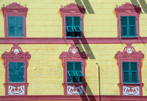 zbliżenie wielokolorowej fasady starego budynku w historycznym centrum rapallo z rzędami zielonych okiennic i dekoracjami trompe l'oeil w kolorach czerwonym i żółtym, genua, liguria, włochy - malarstwo iluzjonistyczne zdjęcia i obrazy z banku zdjęć