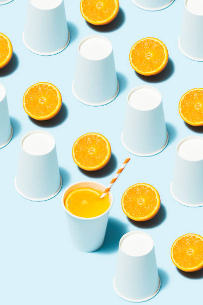 istock Orange juice and white paper cups flat lay on blue background 1163378924