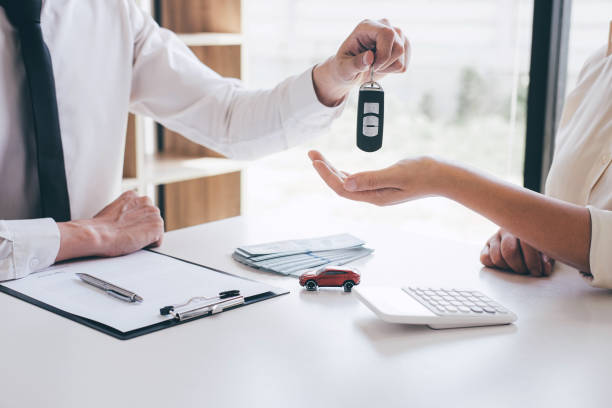 gestionnaire d'agent de location de voiture retenant la clef de la nouvelle voiture donnant au client de femme après avoir signé le contrat de bon accord, louant considérant le véhicule - car car rental car dealership key photos et images de collection