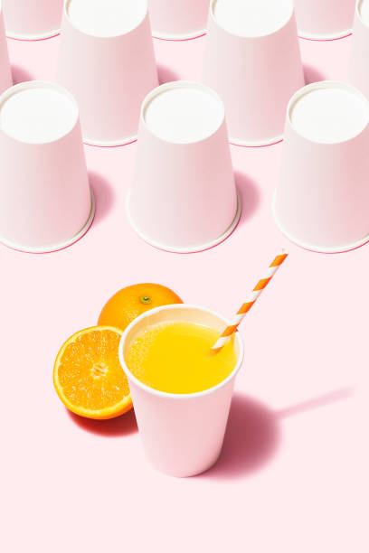 istock Orange juice and white paper cups flat lay on pink background 1163384917