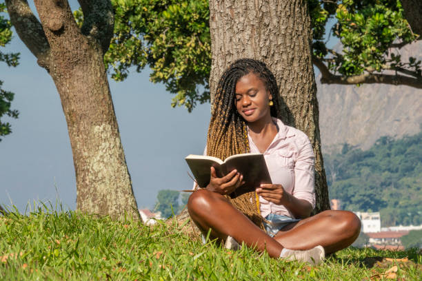 jeune femme noir affichant un livre - parc flamengo photos et images de collection