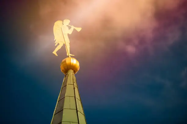 Golden angel windvane on top of church tower in Russia. Blue coudy sky in background.