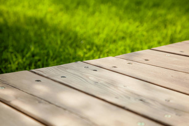 istock Wooden table in diagonal on the image with blurred summer green background 1163388868