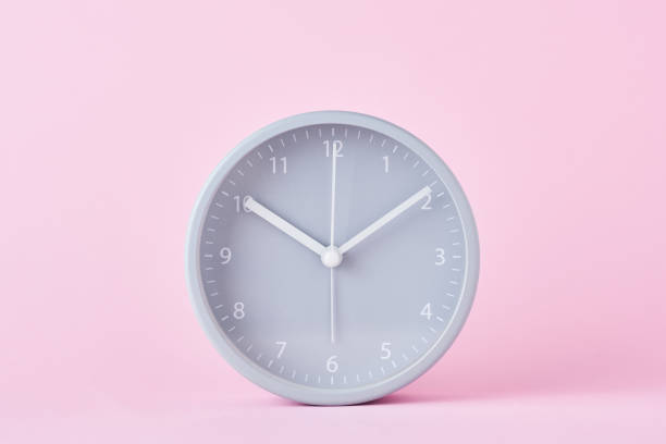 istock Gray classic alarm clock on a pastel pink background, close up 1163389894