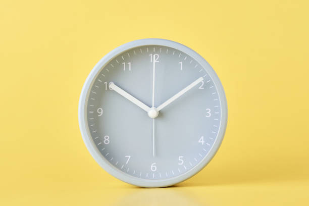 istock Gray classic alarm clock on a pastel yellow background, close up 1163389912