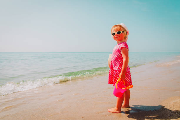 istock cute little girl play with sand on beach 1163389986