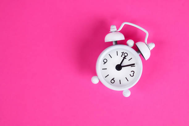 istock White alarm clock pink background. Space copy. Minimal concept. Top view. 1163390166