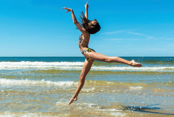 istock Young girl running and jumping on the beach 1163392886