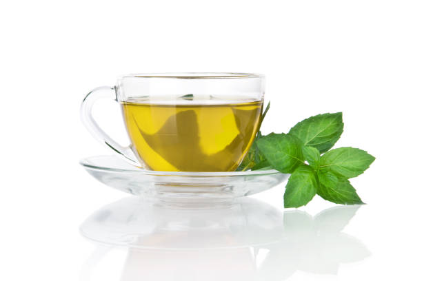tasse mit tee und grünen blättern von minze isoliert auf weißem hintergrund - mint tea lemon tea leaves glass stock-fotos und bilder