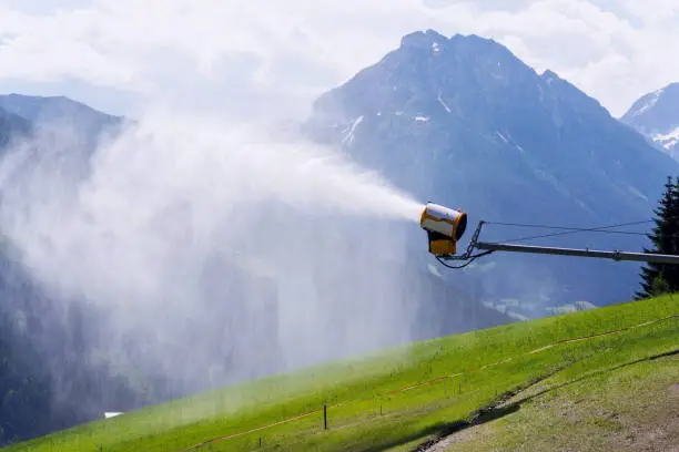 Snow making machines used to water grass on slope, sunny summer day, Wagrain ski resort, Austria