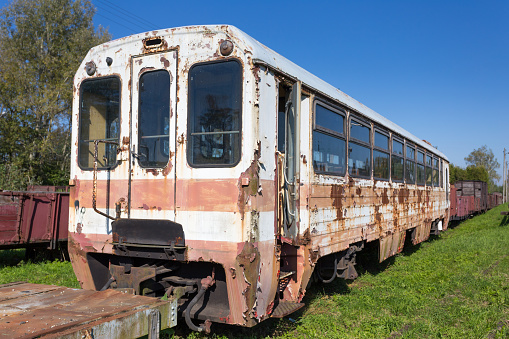 Old ruined steel passenger car. Rusty train on railway tracks.